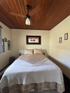 a bedroom with a large bed with a ceiling fan at Chalé Verde Oliva in Camanducaia