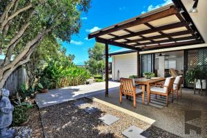 a patio with a table and chairs under a pergola at 2 Settlement Court Bargara QLD 4670 in Windermere