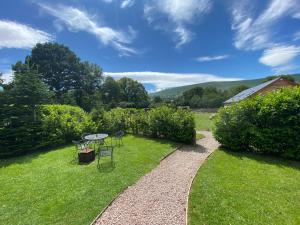a garden with a table and chairs on the grass at unique sheperds hut private hot tub, ensuite & kitchenette in Clodock