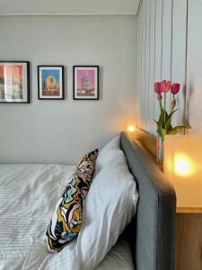 a bed with a pillow and a vase of flowers at Ocean Front Apartment in Busan