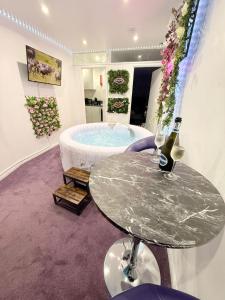 a room with a tub with a table and wine bottles at Guest House Paradise Central in Maidstone