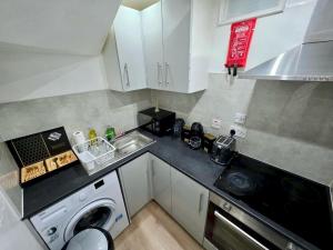 a small kitchen with a sink and a washing machine at Guest House Paradise Central in Maidstone