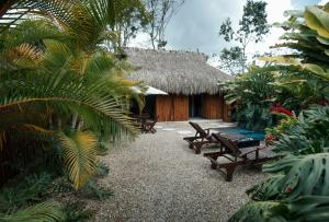 a resort with benches and a thatch roof at Saccharum in Nocaima