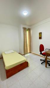 a bedroom with a bed and a desk and a chair at Airport Residence - Vila Acácia I in Praia +5 photos