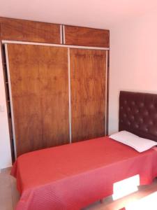 a bedroom with a red bed with a wooden door at Alojamiento El Pucará in San Antonio de Arredondo