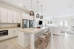 a kitchen with white cabinets and a large island with bar stools at Inlet Beach Reunion House by 30A Escapes in Inlet Beach