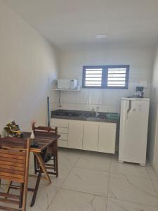 a kitchen with a white refrigerator and a table at Barra do Cunhaú - Barra Mar in Canguaretama