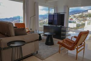 a living room with a couch and a tv at FLH Funchal Bay View Escape with Pool in São Gonçalo