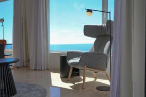 a living room with a chair and a window at FLH Funchal Bay View Escape with Pool in São Gonçalo +32 photos