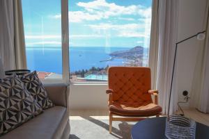 a living room with a couch and a large window at FLH Funchal Bay View Escape with Pool in São Gonçalo