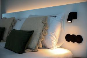 ein Bett mit weißen Kissen und einer Decke darauf in der Unterkunft FLH Funchal Studio Blue View Gardens in São Gonçalo