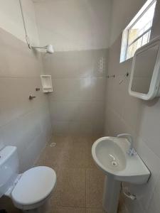 a white bathroom with a toilet and a sink at Pousada Praça da Bíblia - Santa Maria da Vitória in Santa Maria da Vitória