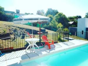 a table and two chairs and an umbrella next to a pool at Alojamiento El Pucará in San Antonio de Arredondo +6 photos