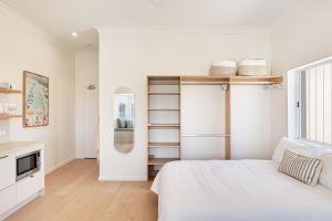 a white bedroom with a bed and a window at Beachfront 1 Bed across from iconic BONDI BEACH in Sydney