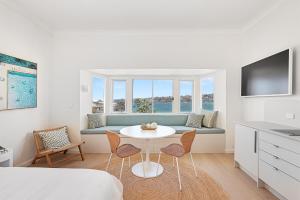 a living room with a couch and a table and chairs at Beachfront 1 Bed across from iconic BONDI BEACH in Sydney