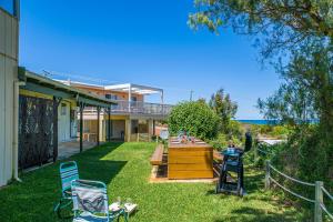 a yard with chairs and a table and a house at Coastal Pine in Guilderton