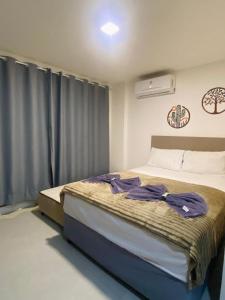 a bedroom with a bed with purple clothes on it at Studio Al Mare - Ocean Blue in Porto De Galinhas