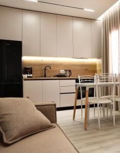 a kitchen with white cabinets and a table and chairs at Meli Deluxe Apartments in Tirana