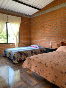 two beds in a room with a brick wall at Villa Pospon in Buga +13 photos