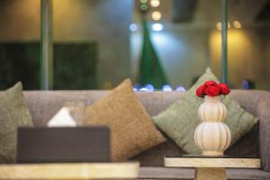 a vase with red flowers in it sitting on a table at فندق بارك الياس in Aţ Ţunḑubāwī +14 photos