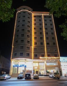 a tall building with cars parked in front of it at فندق بارك الياس in Aţ Ţunḑubāwī
