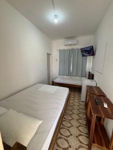 a bedroom with a large bed and a table at Pousada Praça da Bíblia - Santa Maria da Vitória in Santa Maria da Vitória