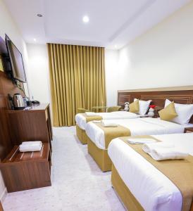 a hotel room with four beds and a television at فندق بارك الياس in Aţ Ţunḑubāwī