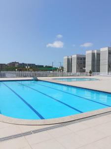 a large swimming pool with blue water in front of buildings at Quarto privativo in São-José-do-Ribamar