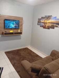 a living room with a couch and a flat screen tv at Meu Cantinho in Botucatu