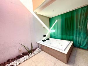 a bathroom with a bath tub and a pink wall at Sensacional Suíte no Union no Jacaré! in Ilha da Restinga