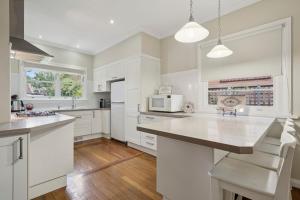 a kitchen with white cabinets and a large island at Balgownie Cottage in Blackheath