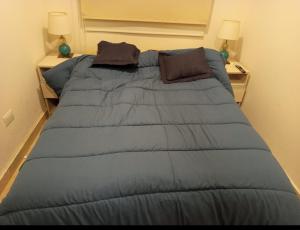 Una cama con un edredón azul en un dormitorio. en Hermosa casa amoblada en barrio privado, en Yerba Buena
