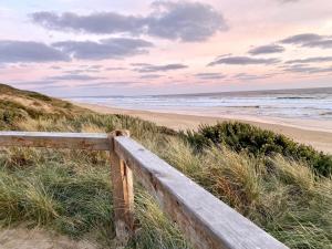 a wooden fence on a beach with the ocean at Bella's Beach House in Venus Bay