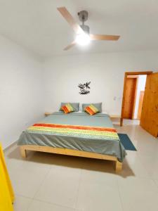 a bedroom with a bed with a ceiling fan at Casa Colibri - Confort et Authentique, à 300m de la plage ! in Mindelo