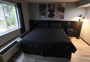 a bedroom with a black bed and a window at Plymouth Suites in Plymouth
