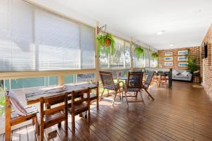 a dining room with tables and chairs and windows at Dolphin Cove - Pet Friendly with Fireplace in Callala Bay