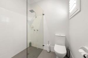 a white bathroom with a toilet and a shower at Dolphin Cove - Pet Friendly with Fireplace in Callala Bay +19 photos