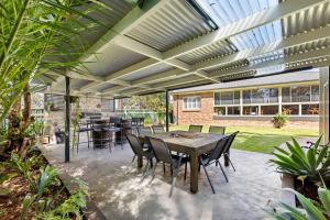 a patio with a wooden table and chairs at Dolphin Cove - Pet Friendly with Fireplace in Callala Bay