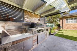 an outdoor kitchen with a grill in a backyard at Dolphin Cove - Pet Friendly with Fireplace in Callala Bay