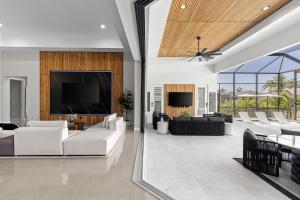 a living room with white furniture and a flat screen tv at Modern Luxury Oasis Pool and Dock in Cape Coral