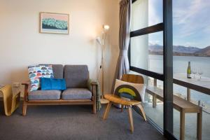 a living room with a couch and a view of the water at Hello QT Lakeside Gem in Queenstown