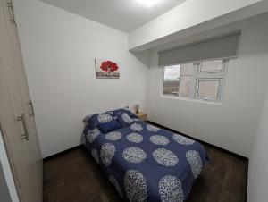 een slaapkamer met een bed met een blauw dekbed en een raam bij Casa Milos in Guatemala