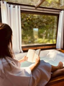 a woman sitting on a train reading a book at Maria Rita dos Canyons in Praia Grande