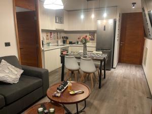 een woonkamer met een bank en een tafel en een keuken bij Puerto Montt Centro - Diagonal Germania in Puerto Montt +2 foto's