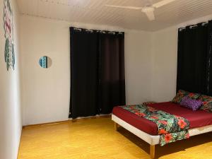 a room with a bed in a room with black curtains at HeiAki Lodge Excursion Nukuhiva Chambre Hei in Nuku Hiva