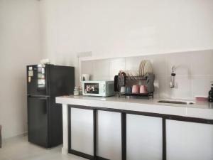a kitchen with a black refrigerator and a white counter top at Sofia roomstay 2 in Kampong Beris Meraga +3 photos