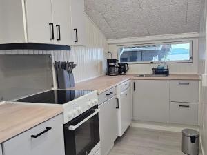 eine Küche mit weißen Schränken und einer Spüle in der Unterkunft Family-Friendly Cottage Near the Coast in Tirsbæk