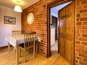 a dining room with a table and a brick wall at Dabinett in Ledbury