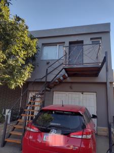 a red car parked in front of a house at Microbed in Cipolletti