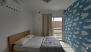 a bedroom with a bed with a blue wall with clouds at Apartamento 3 quartos prox passeio Pedra Branca in Palhoça